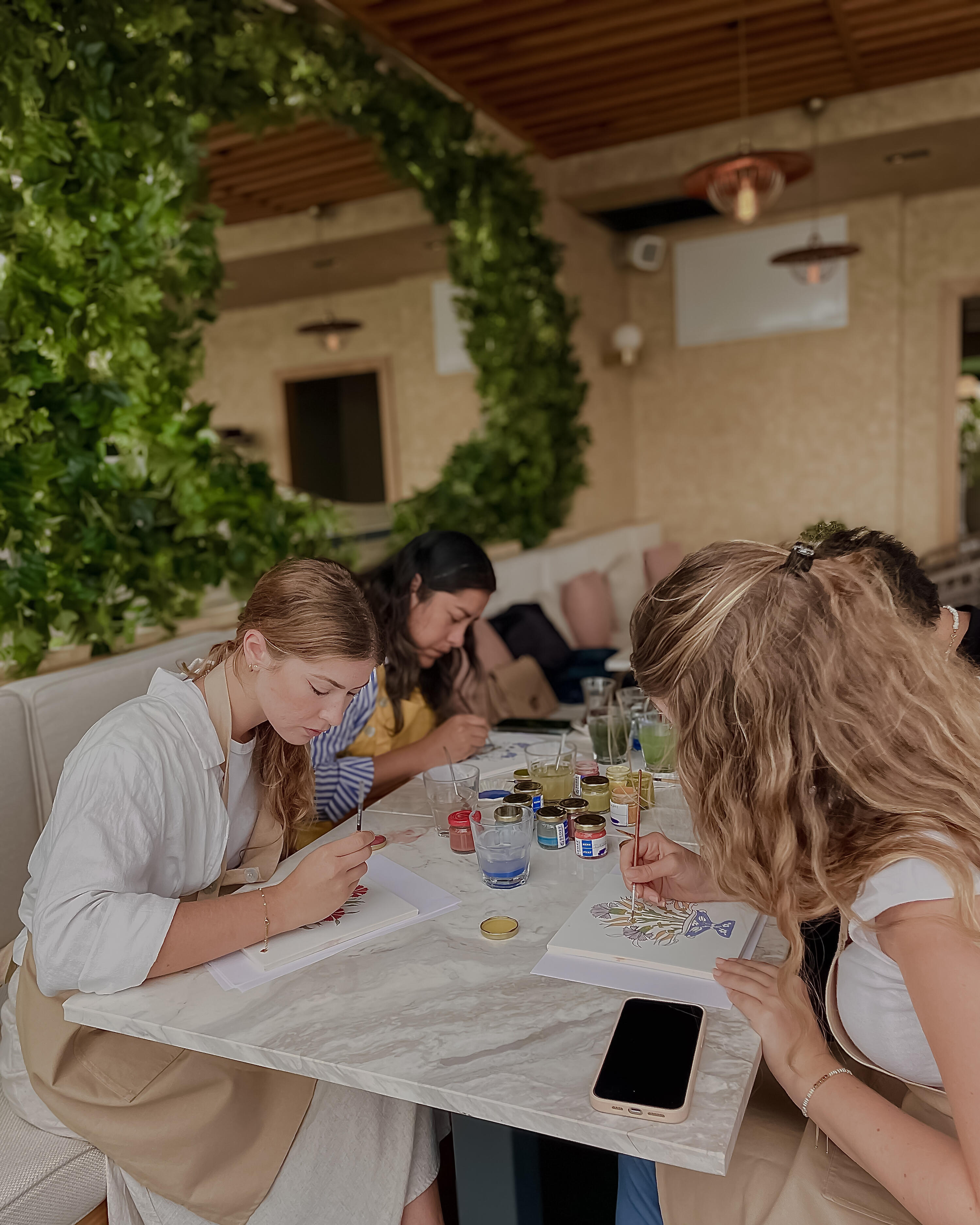 Women painting ceramic tiles on the table