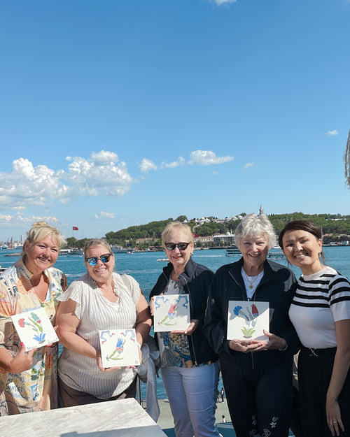 Group of people holding ceramic square tiles and smiling at the camera